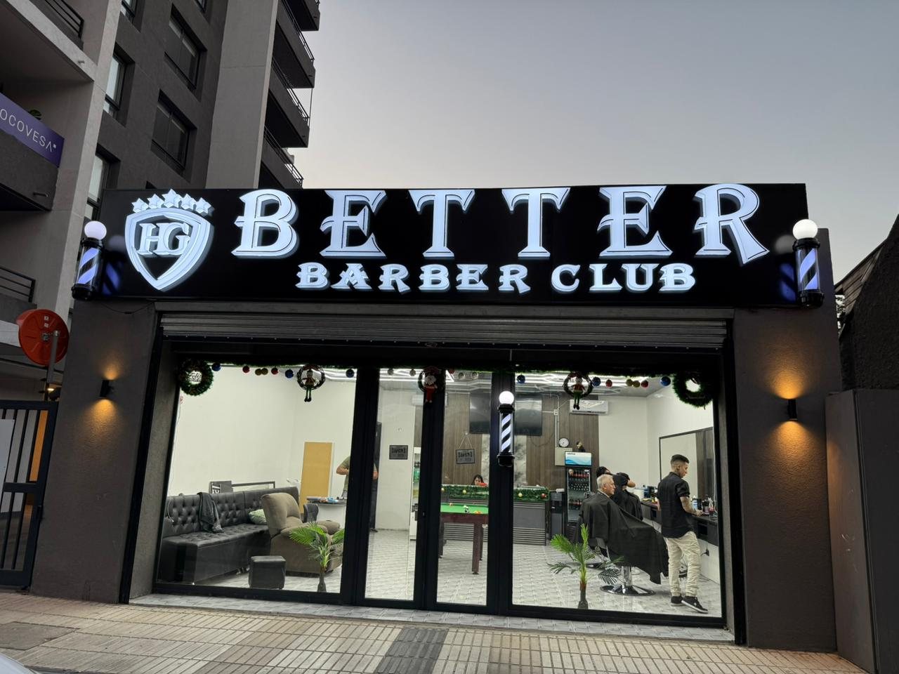 Fachada iluminada de Better Barber Club de noche